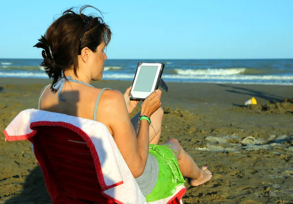 Femme lit l'ebook sur la plage au bord de la mer en été — Photo