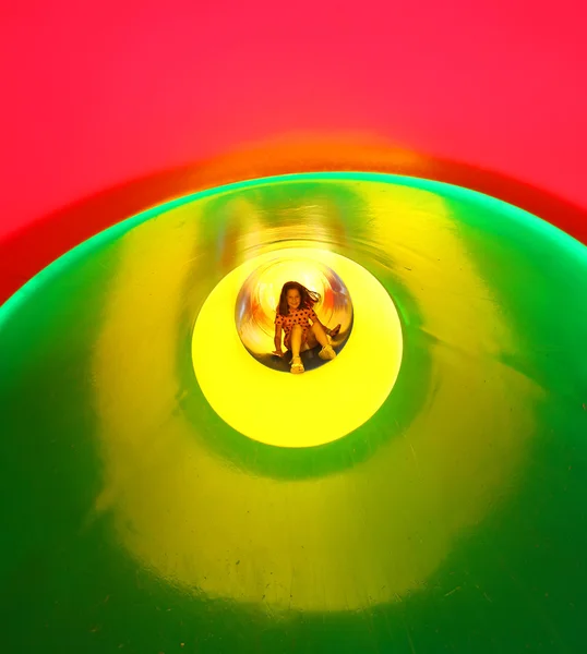 Smiling little girl down the slide of a playground — Stock Photo, Image