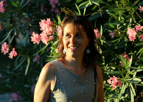 Kvinnan vid solnedgången och oleander blommor — Stockfoto