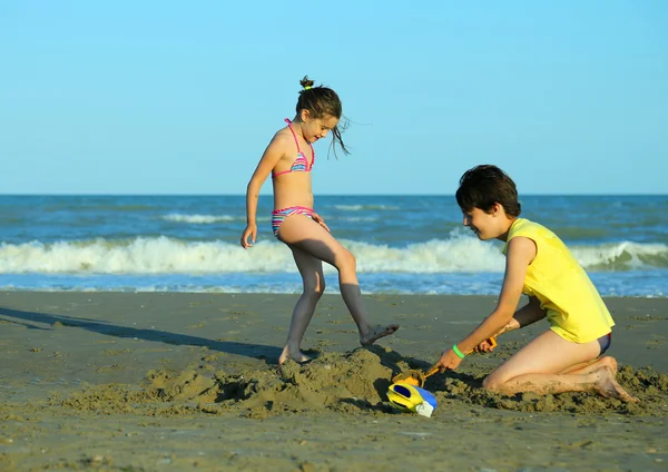 Menina e seu irmão brincar com água na praia no summ — Fotografia de Stock