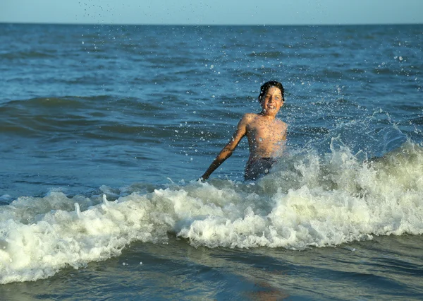 Szczęśliwy chłopiec gra skacząc na falach — Zdjęcie stockowe