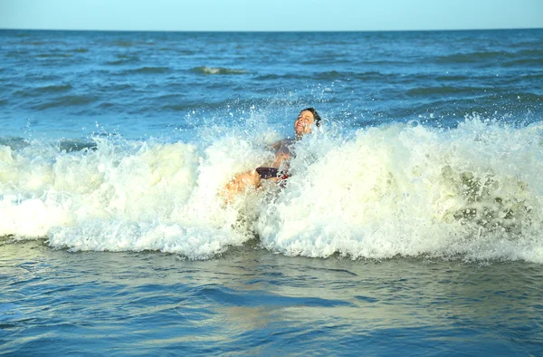 Felice ragazzo gioca saltando le onde del mare — Foto Stock