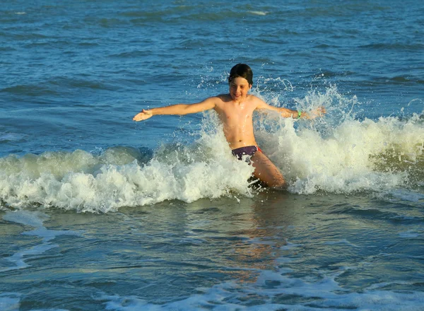 Νεαρό αγόρι παίζει υπερπηδώντας τα κύματα — Φωτογραφία Αρχείου