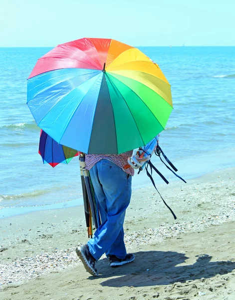 Hausierer von Sonnenschirmen am Strand im Sommer — Stockfoto