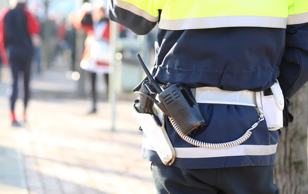 Policeman in uniform with a radio transmitter and gun during a d — Stock Photo, Image