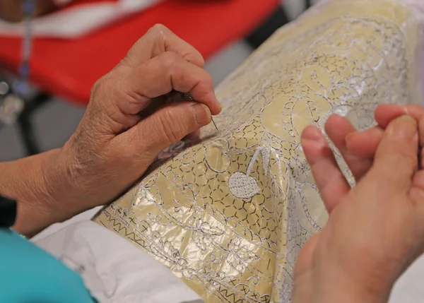 Руки пожилых людей во время вышивки кружева с кружевной подушкой — стоковое фото