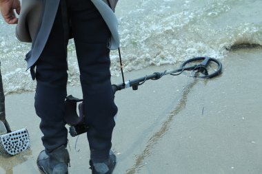 Adam sahilde metal dedektörü ile kayıp nesneleri bulmak için