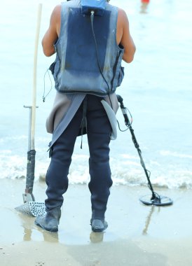 Adam metal dedektörü ile kum altında kayıp nesneleri bulmak için 