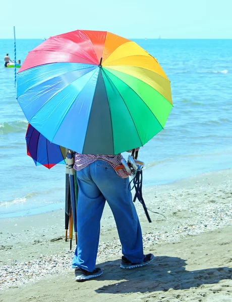 Armer Hausierer von Sonnenschirmen am Strand — Stockfoto