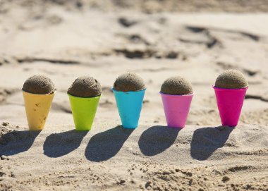 Beş oyuncak dondurma koni kum ile deniz sahilde