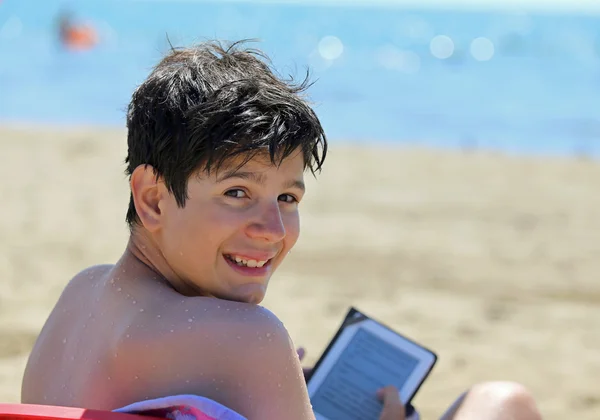 Jongen leest de ebook op het strand — Stockfoto