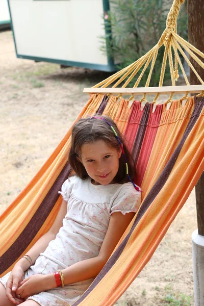Beautiful little girl with long brown hair resting on a hammock — Stock Photo, Image