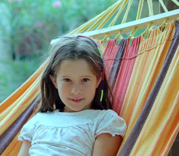 Χαριτωμένο μικρό κορίτσι, με μακριά καστανά μαλλιά, στηρίζεται σε μια αιώρα — Φωτογραφία Αρχείου