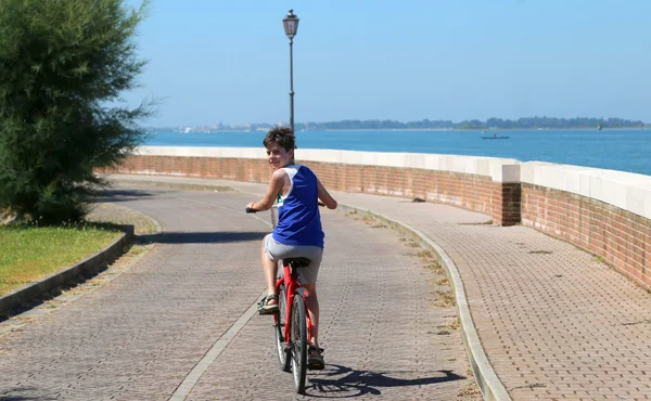 Young boy rides on the bike path near — Stock Photo, Image