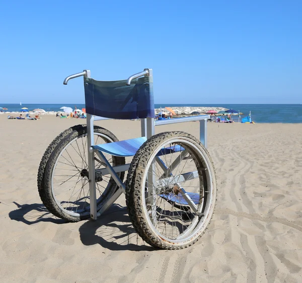 Silla de ruedas en la playa de arena cerca del mar —  Fotos de Stock