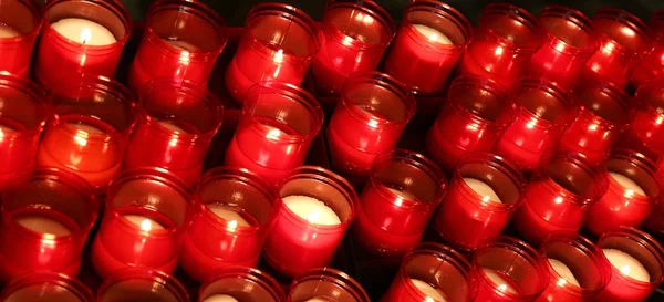 Many red flames of candles lit by the faithful in the place of w — Stock Photo, Image