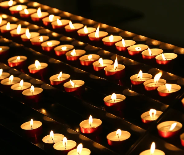 Veel kaarsen verlicht met flakkerende vlam in de plaats van gebed — Stockfoto
