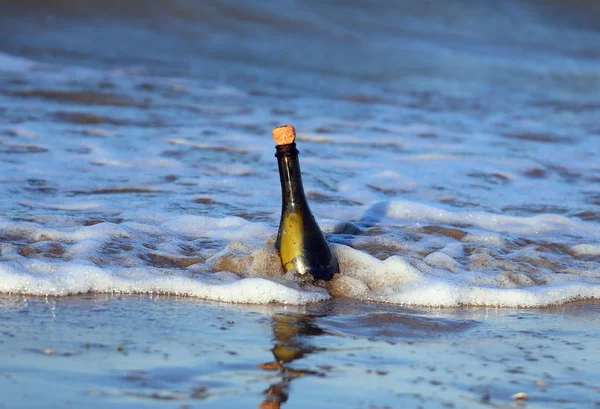Стеклянная бутылка на пляже с секретным сообщением — стоковое фото