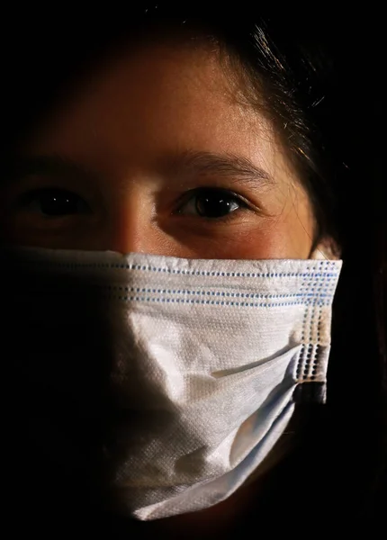 若いですかわいいです外科マスクを持つ女の子から身を守るためにパンデミックからCovid 19ウイルス劇的な黒の背景に — ストック写真