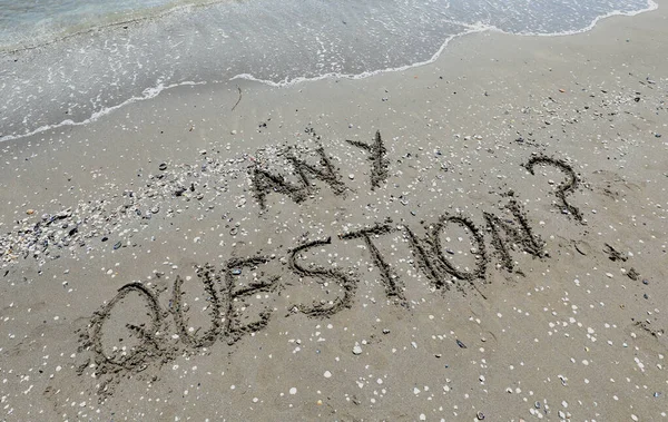 ANY QUESTION  text written on the sand of the beach by the sea