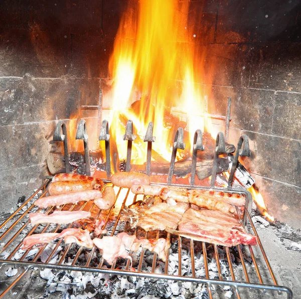 ソーセージとステーキを混ぜ合わせたグリルを調理しながら暖炉の大きな炎 — ストック写真