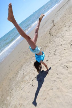 Genç atletik kızlar yazın deniz kıyısında egzersiz ve dönüş yaparken.