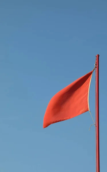 青空を背景に危険を示すために手を振っている赤い旗 — ストック写真