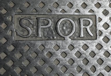 Metal rögar kapağındaki SPQR metni İtalya 'daki Roma şehrinin kısaltmasıdır ve İtalyan dilinde Roma Senatosu ve Halk anlamına gelir.