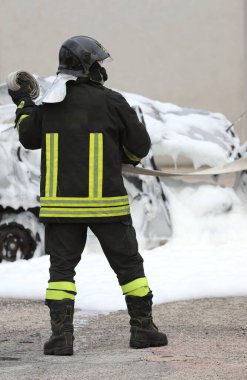 Üniformalı ve kasklı itfaiyeci araba kazasından sonra köpüklü bir arabayı ateşe verdi.