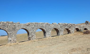 Antik Roma su kemerleriyle yapılmış ve İtalya 'daki Antik Roma şehrine su getirmek için doğru eğimle tarlanın ortasında uzanan bir su kemeri.