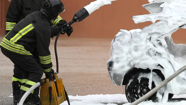 Πυροσβέστες Σβήνουν Φωτιά Ενώ Ένα Τρακαρισμένο Αυτοκίνητο Αφρό Μετά Τροχαίο — Φωτογραφία Αρχείου