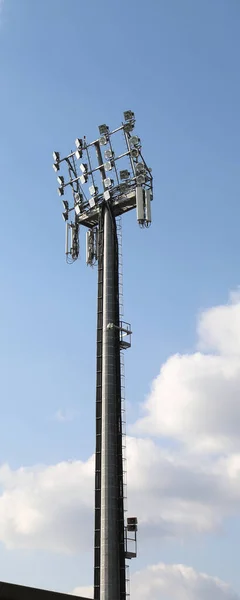 電話信号を繰り返すために使用される多くの明るい反射板と携帯電話アンテナを備えたスポーツ施設のライトタワー — ストック写真