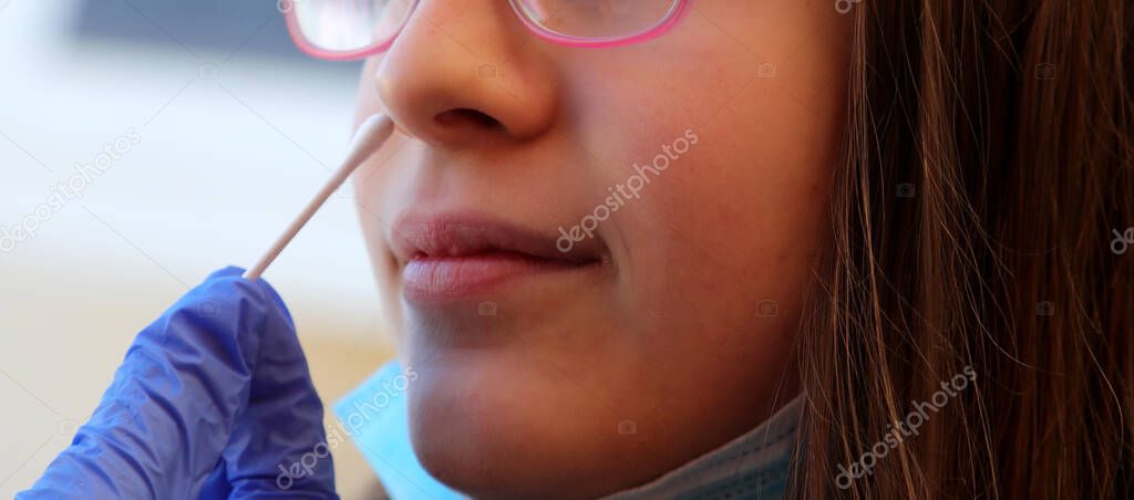 young caucasian girl in the clinic makes a swab in the nose to look for coronavirus