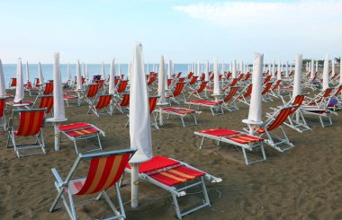 Yaz mevsiminde plajda turistleri bekleyen insanlar olmadan şemsiyeler ve şezlonglar.