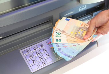 ATM makinesinden bir sürü para çekilen el ve PIN kodu yapmak için sayısal tuş takımındaki numaralar