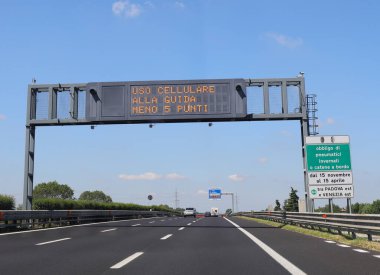 highway sign indicating the prohibition to use the mobile phone while driving is a sign that says to always have snow chains on board the car in Italy clipart