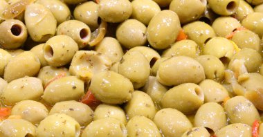 background of green olives in brine for sale in the street market stalls of southern Italy