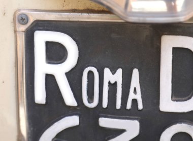 large text ROMA on an old license plate of a car in the capital city of Italy