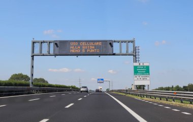 motorway sign with the inscription in Italian which means that points are deducted from the driving license if the driver drives the car with a mobile phone in italian language clipart
