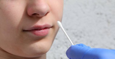 Hemşireler salgın sırasında küçük kıza koronavirüs virüsü araması için genizden örnek alırlar.