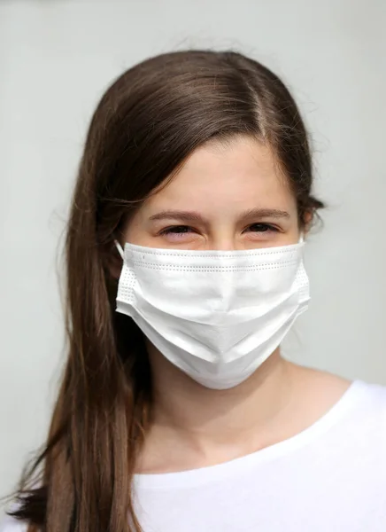 白いマスクをした茶色の髪の美しい少女コロナウイルスから身を守るために — ストック写真