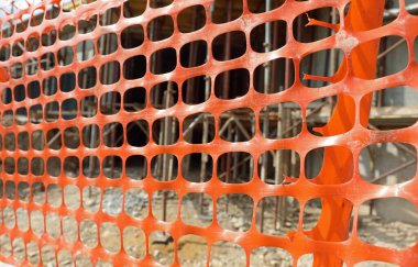 Enerji tasarrufu için gerekli materyallerin bulunduğu bir binanın yapımı sırasında inşaat alanının korunması için turuncu plastik ağ