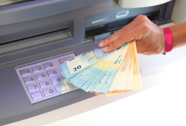 Euro banknotları ATM 'den çekildi ve PIN' e girmek için onları rakamsal tuş takımı ile alan el...