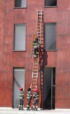 fire brigade team performing an exercise in using the stairs to reach the upper floors of the house and enter through the windows clipart