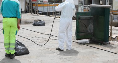 Koronavirüs salgını sırasında beyaz önlüklü işçiyle birlikte sokak mobilyalarının dezenfekte edilmesi