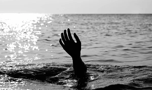 hand of the drowning person in the middle of the ocean in black and white to make the effect more dramatic