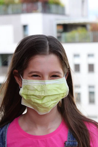コロナウイルスから身を守るために長い黒い髪と緑のマスクを持つ素敵な女の子 — ストック写真