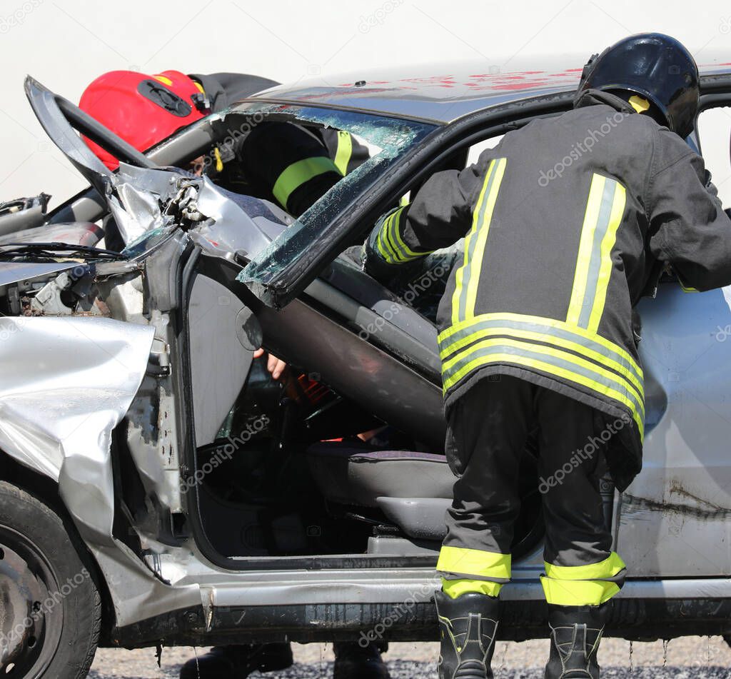 Firefighters during the rescue after the crash and the broken car