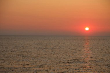Çok sıcak bir gün batımı tonu. İçinde insanlar olmadan denizin içinde barınan güneşle birlikte.