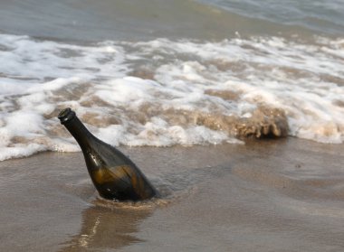Gizli bir mesajı ya da deniz kenarındaki hazine haritasını saklayan karaya vurmuş cam bir şişe.